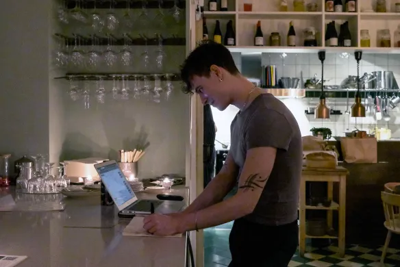 Man staat voor laptop met notitieblokje